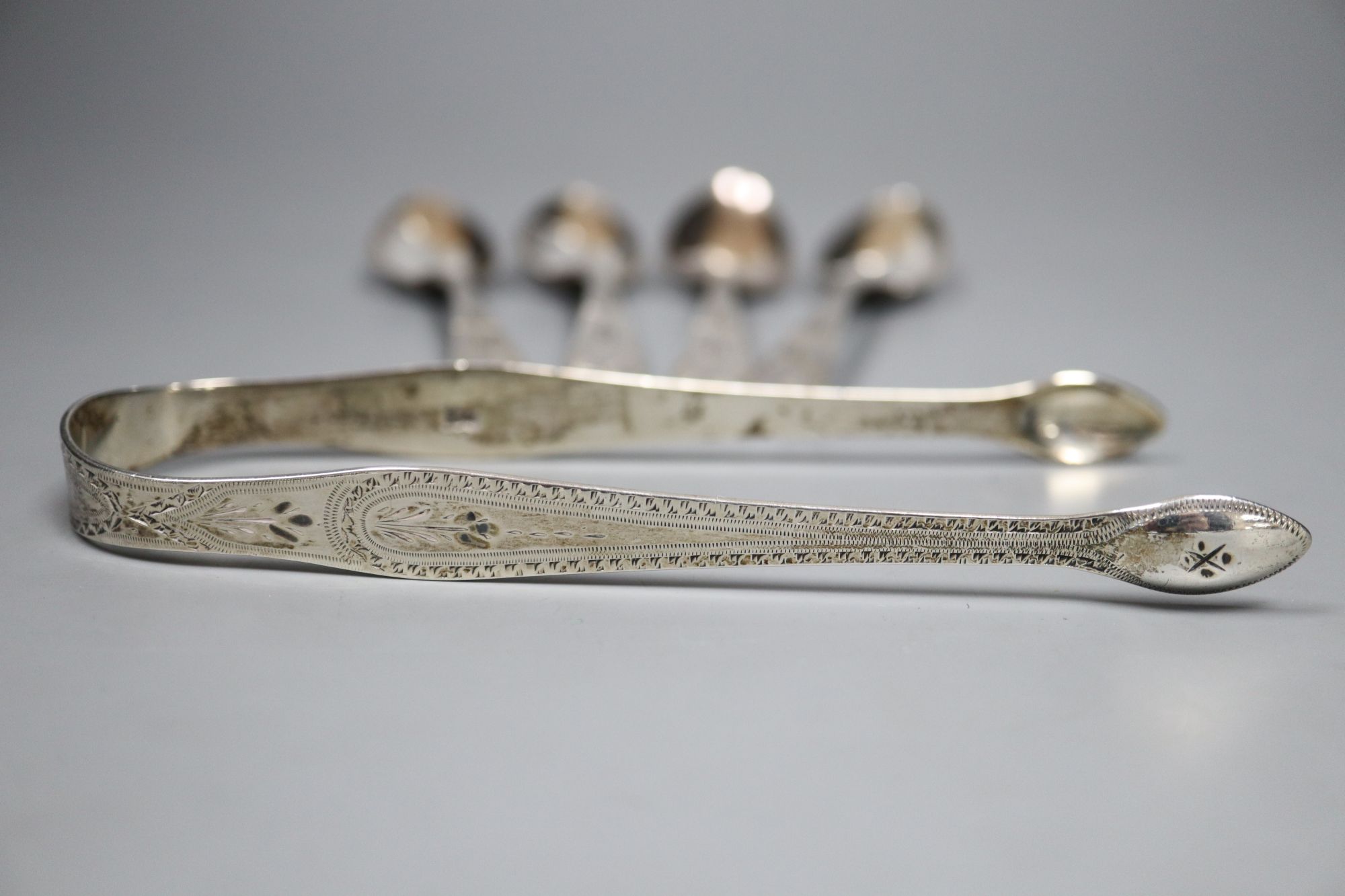A pair of George III silver bright cut sugar tongs, by Hester Bateman and a set of four similar teaspoons, London, 1796
